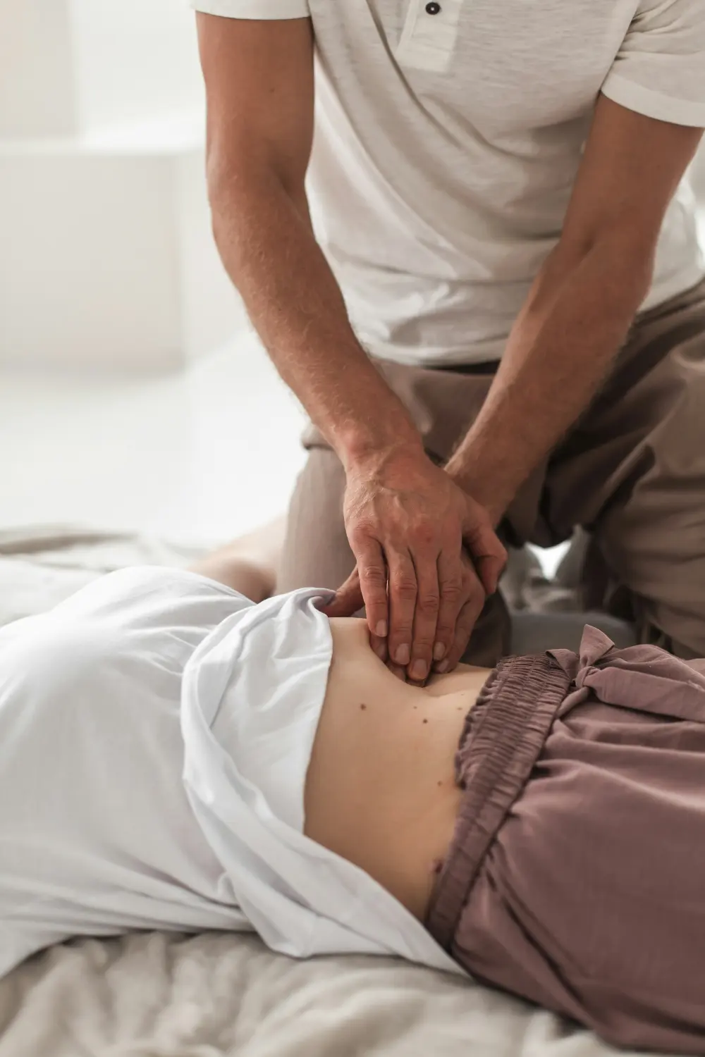 A physio's hands working on a patient's lower back